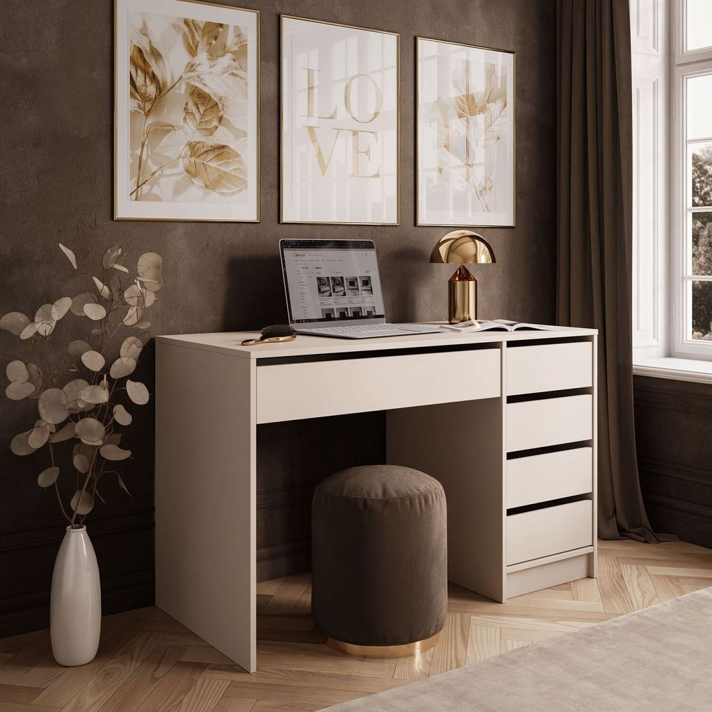 A modern desk setup with a laptop, lamp, and artwork on a dark wall.