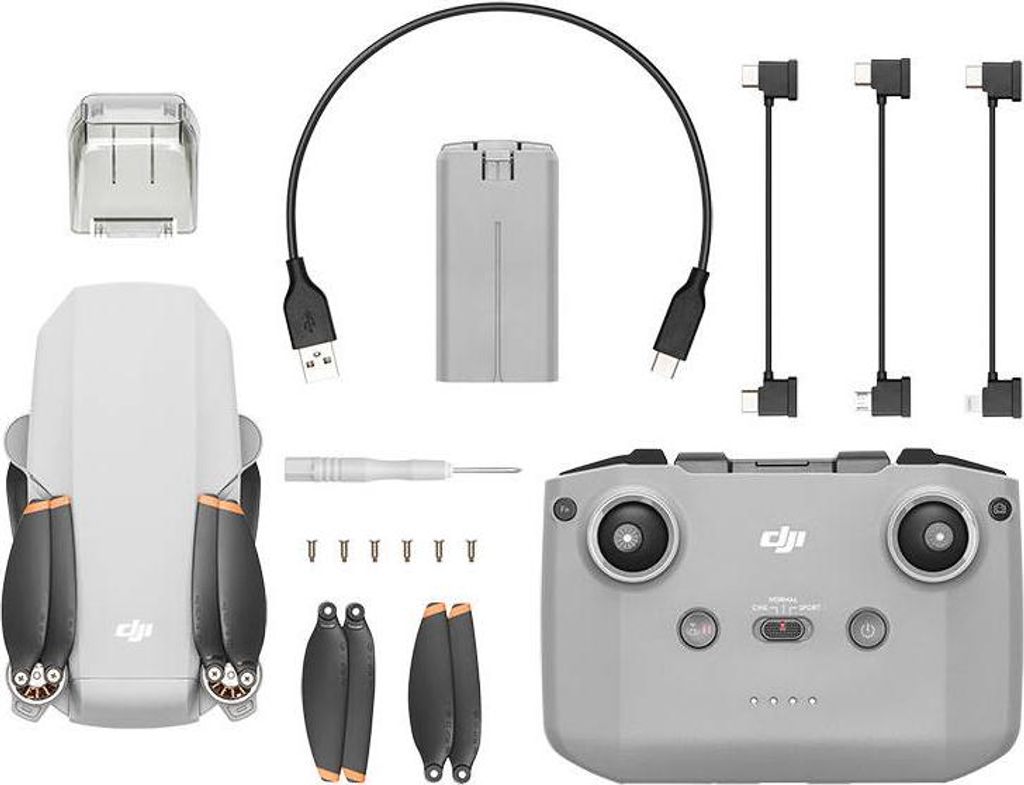 A flat lay of a drone and its accessories, including a remote control, battery, charging cable, propellers, and a small screwdriver.