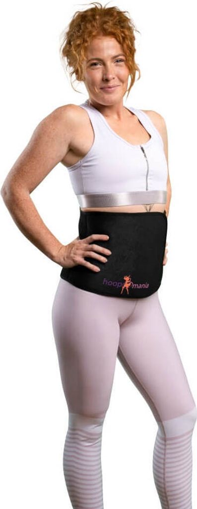 A woman is posing in athletic wear, wearing a black waist trainer.