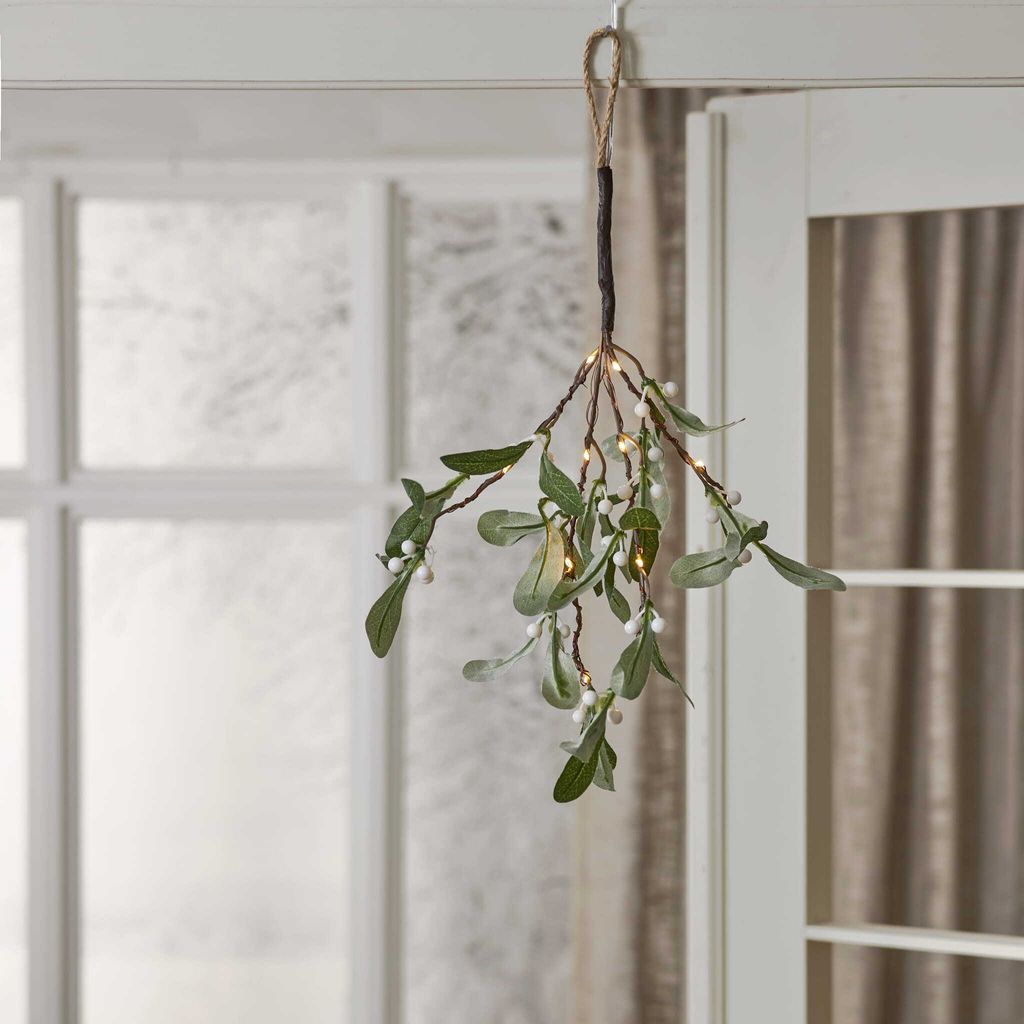 A decorative mistletoe branch with LED lights hangs from a hook.