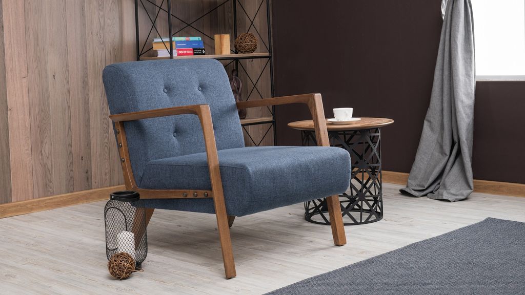 A blue armchair with wooden legs sits in a room with a bookshelf in the background.
