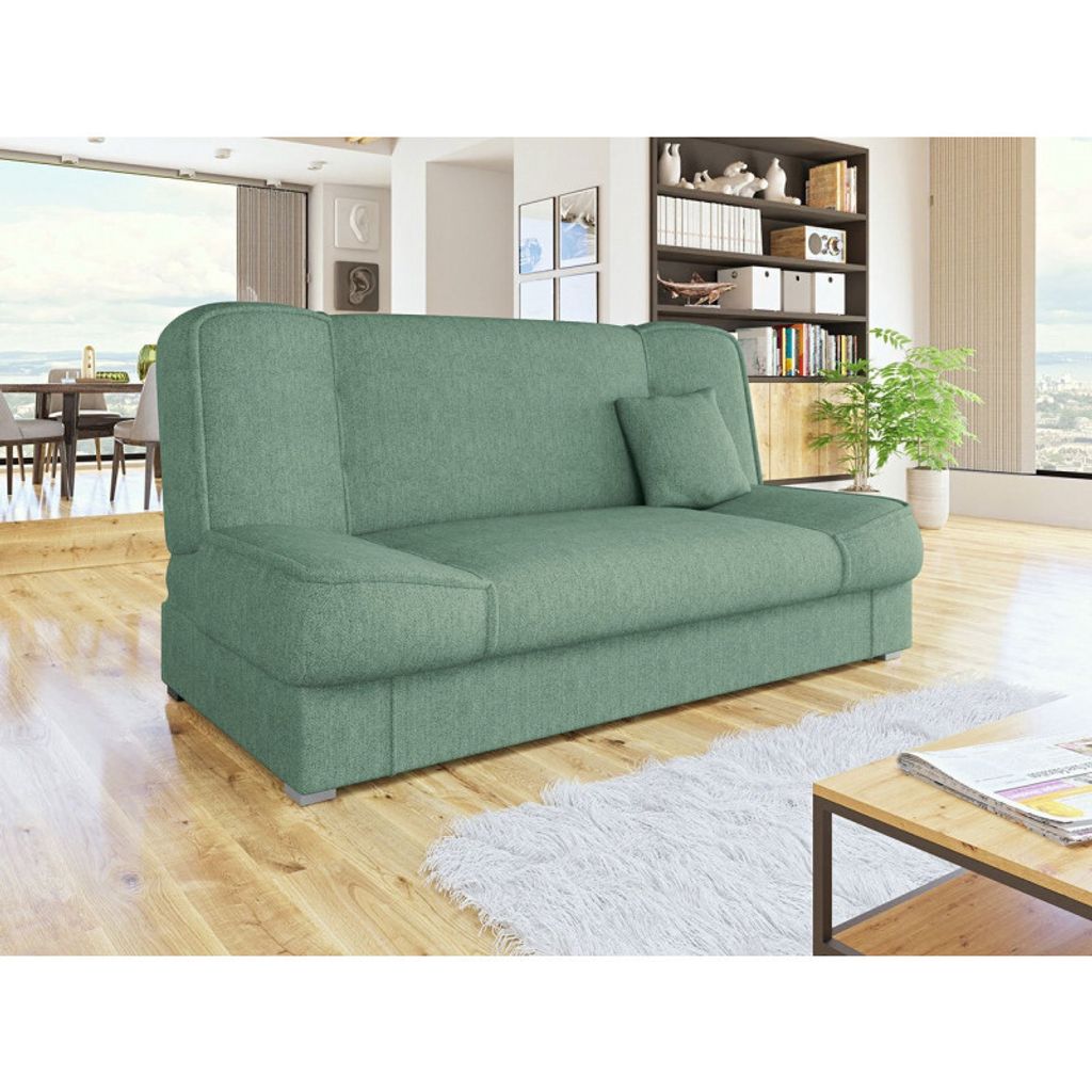 A green sofa is shown in a living room setting with a dining area in the background and a bookshelf on the right.