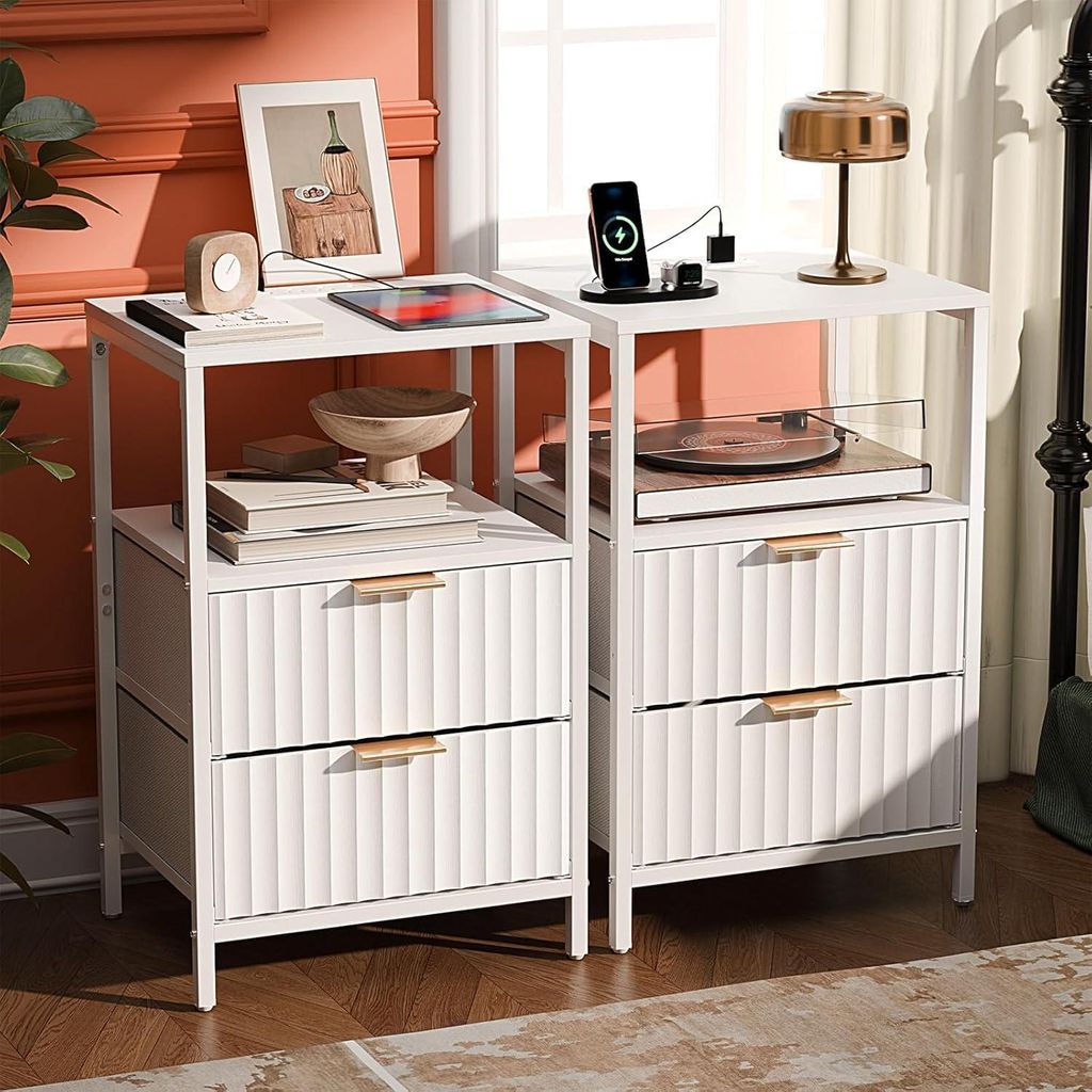 Two white nightstands are shown in a bedroom setting, with decorative items and electronics on top and within.