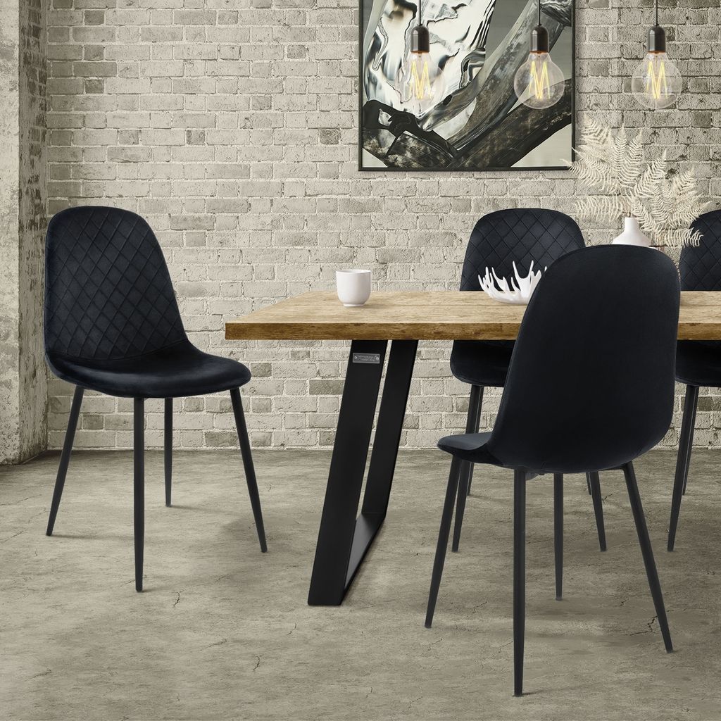 A dining room scene with a wooden table and black velvet chairs.