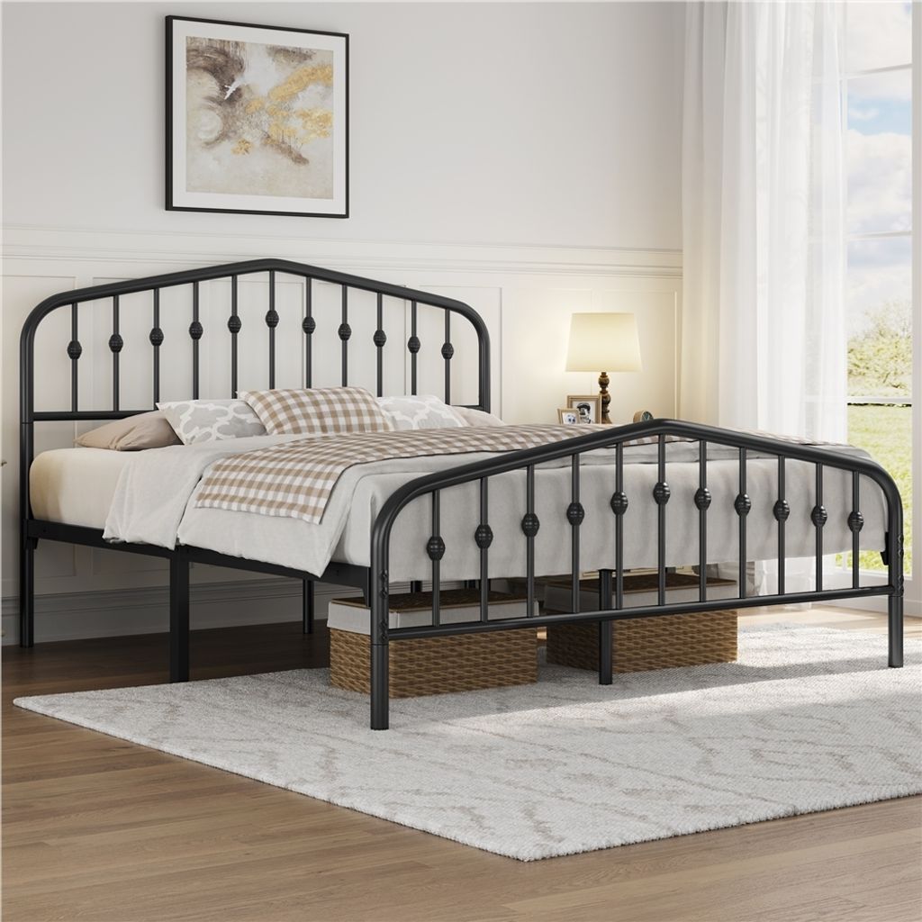 A black metal bed frame with a headboard and footboard, set up in a bedroom with bedding and a rug.
