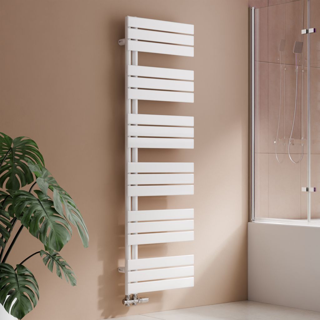 A white designer towel radiator is mounted on a light brown wall in a bathroom setting, with a large green plant to the left and a shower enclosure to the right.
