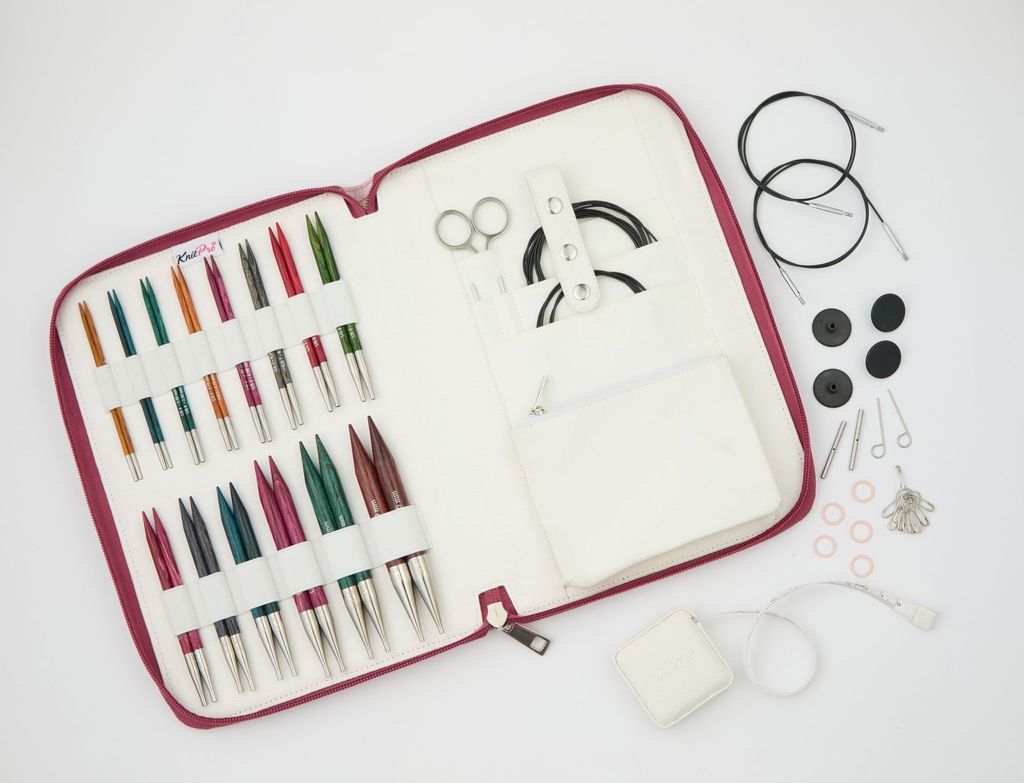 An open knitting needle set case with various knitting needles and accessories laid out on a white background.
