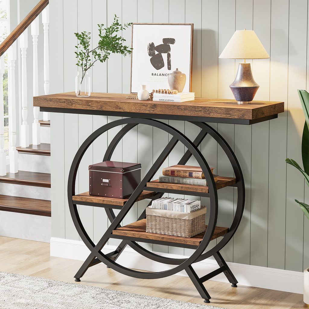 A console table with a wooden top and a geometric metal frame with shelves, placed in a home entryway next to stairs.