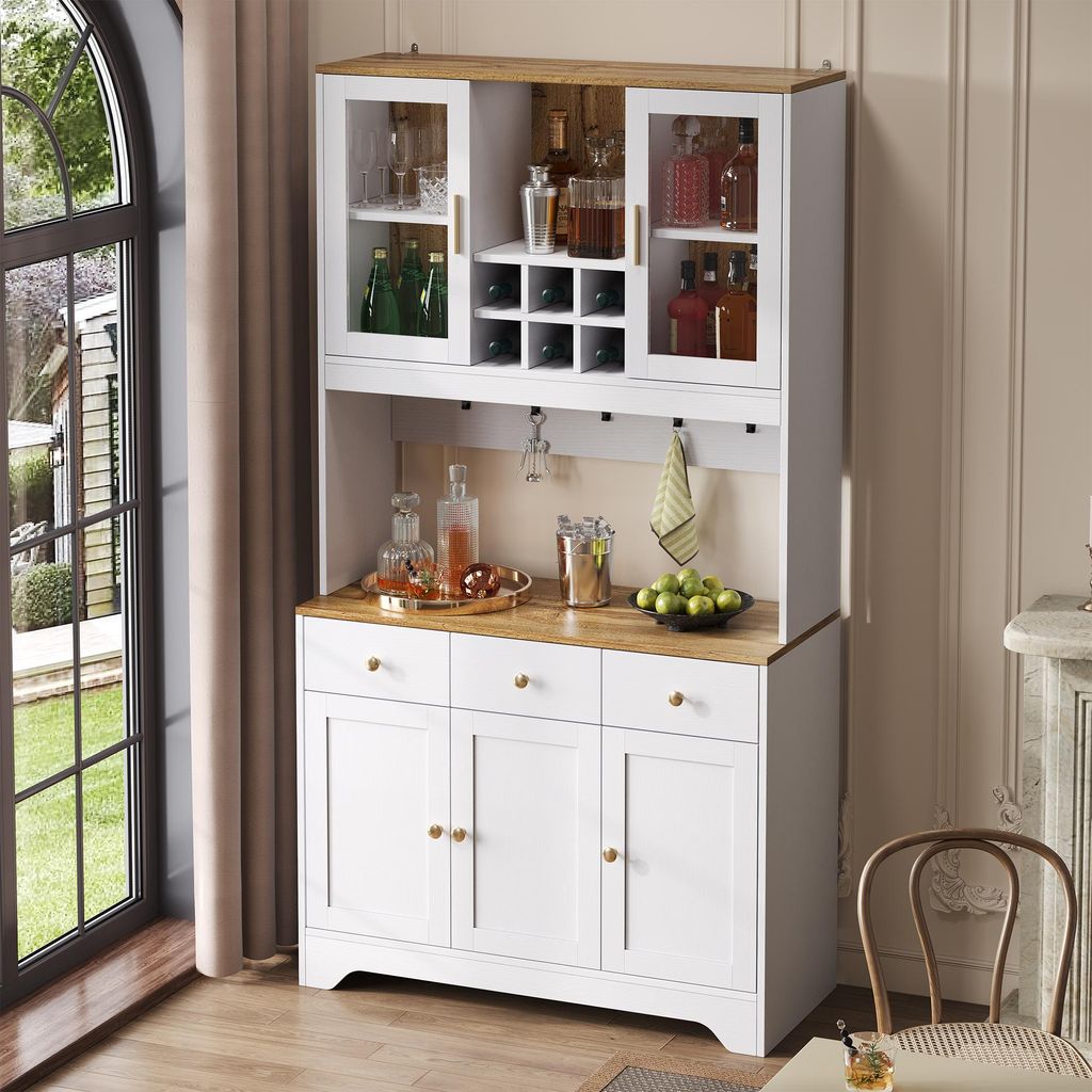 A white and wood sideboard with glass doors and drawers, filled with bottles and glassware, is shown in a room setting.