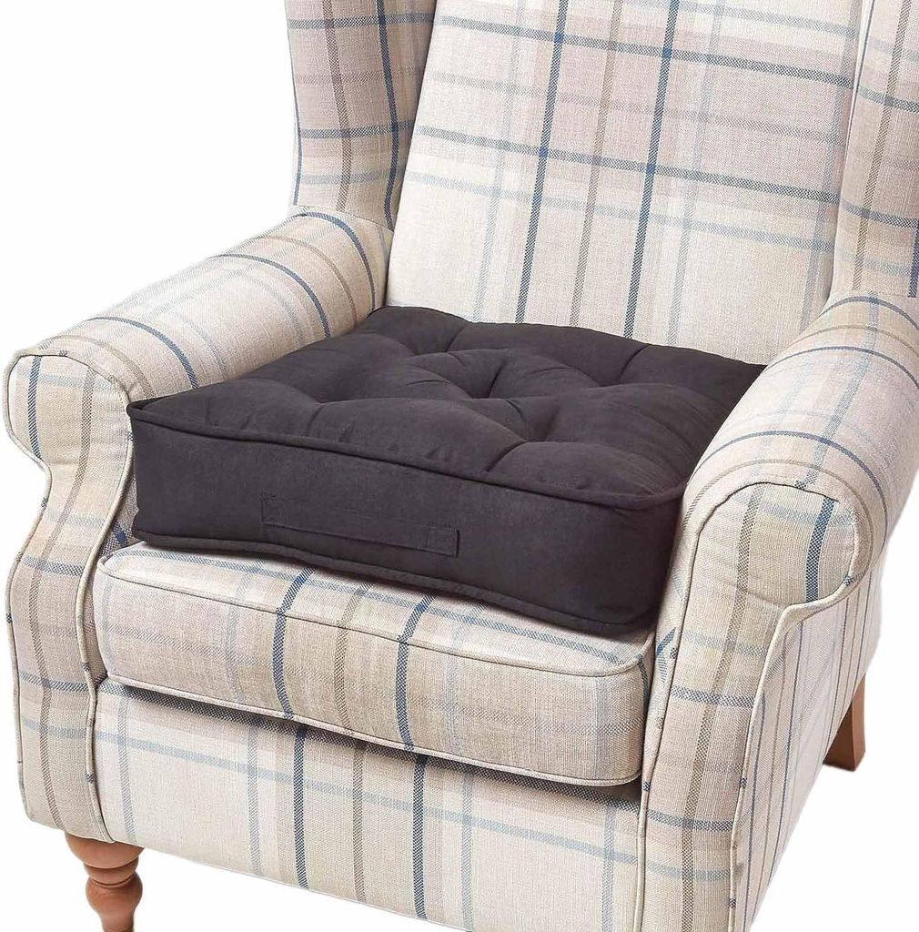 A dark grey seat cushion is placed on a beige and blue plaid armchair.