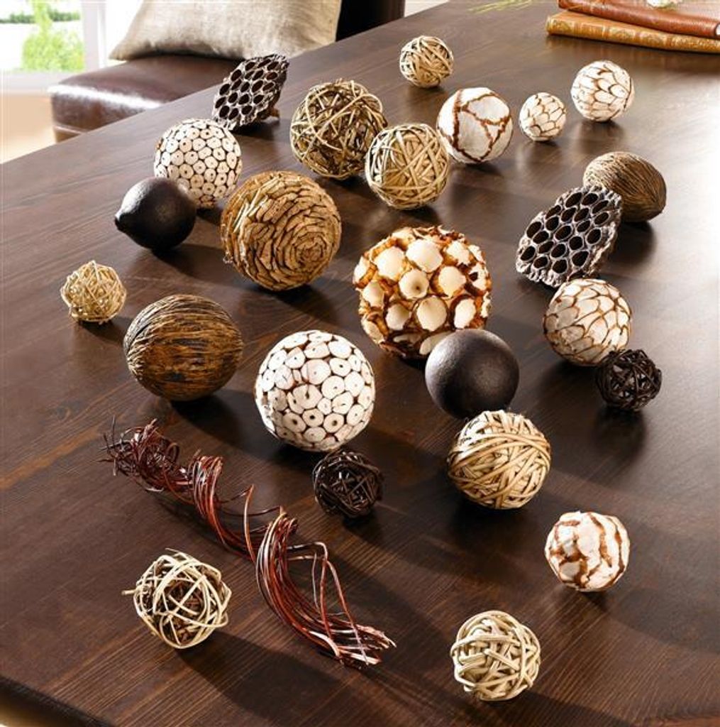A collection of decorative balls made from natural materials arranged on a wooden table.