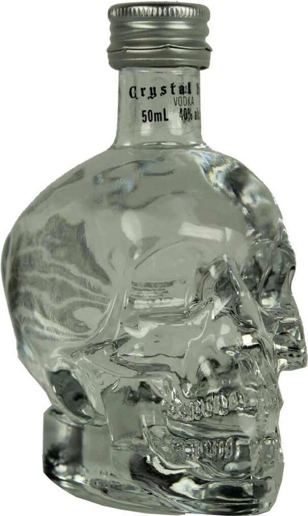 A clear glass bottle shaped like a skull, containing clear liquid, with a silver cap.