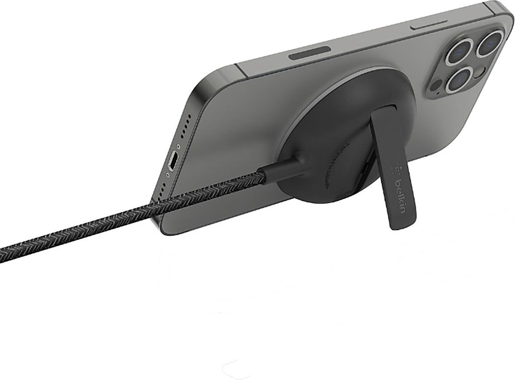 A smartphone is attached to a black charging accessory with a kickstand, and a braided USB-C cable is plugged into the phone.