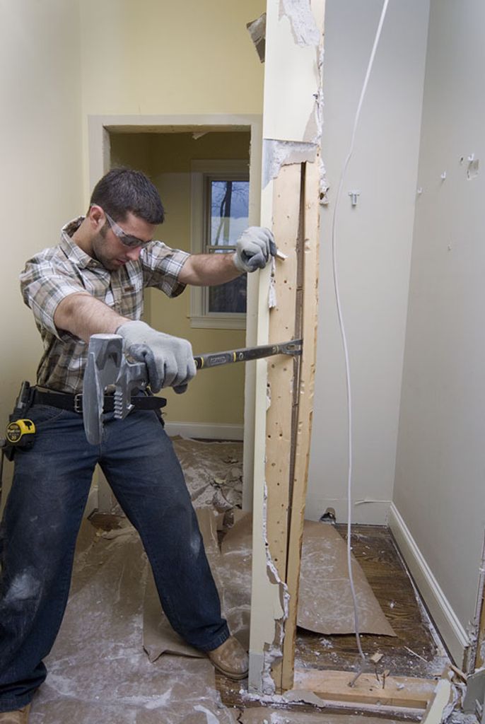 A man is using a demolition tool to break down a wall.