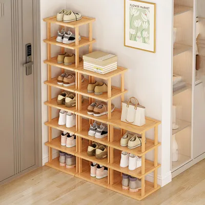 A multi-tiered wooden shoe rack filled with various shoes, placed next to a door and a wall with a picture frame.