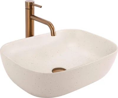 A beige countertop sink with a gold faucet.