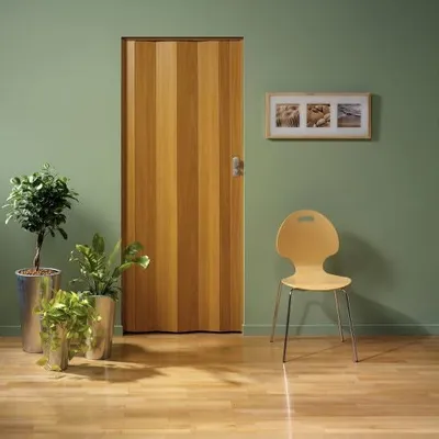 A wooden folding door is shown in a room with plants and a chair.