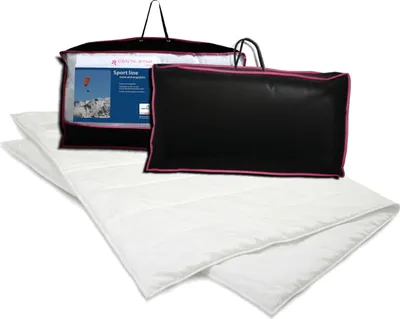 A white duvet is laid out in front of two black zippered bags with pink trim, one of which contains a product insert.