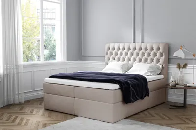 A bedroom scene with a bed, window, and side table.