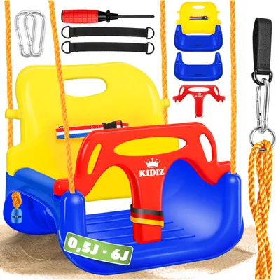A product shot of a colorful baby swing set and its accessories, laid out on a sandy surface.