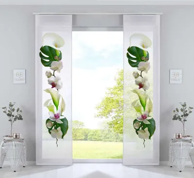 Two panel curtains with floral designs are displayed in a room with a window view of greenery.