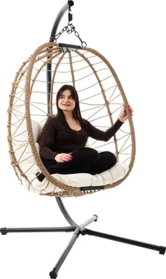 A woman is sitting in a hanging egg chair.