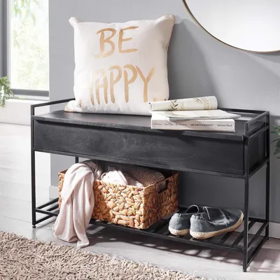 A bench with storage in a hallway or entryway, styled with a pillow and books on top, and a basket with blankets and shoes below.