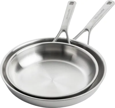 Two stainless steel frying pans stacked on top of each other, with their handles pointing upwards and to the right. The pans are clean and shiny, reflecting light.
