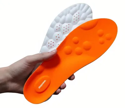 Eine Hand, die ein Paar orange-weiße Schuheinlagen mit strukturierten Oberflächen hält