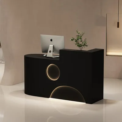 A modern black reception desk with integrated lighting and a computer.