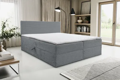 A VENASI TILLY Boxspringbett 180x200 with storage compartments and H2/H3 mattress in gray cord fabric is shown in a bedroom setting.