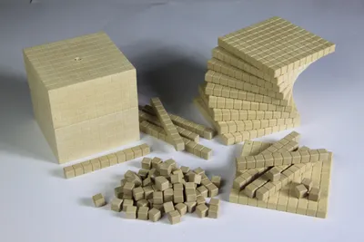 A collection of wooden blocks and rods, representing units, tens, and hundreds, used for math education.