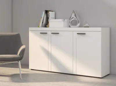 A white sideboard with three doors is shown in a room with a gray chair.