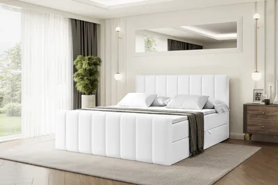 A white upholstered bed with storage drawers in a bedroom setting.