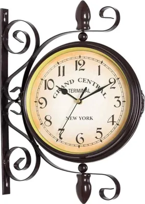 A double-sided antique-style station clock mounted on a decorative wrought iron bracket.