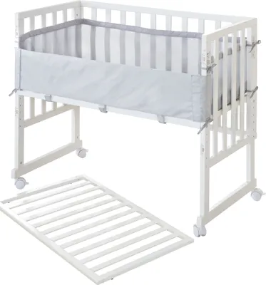 A white crib with a gray and white striped liner is shown with a detached wooden base.