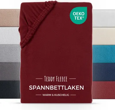 A folded red fitted sheet with a label and other colored sheets in the background.