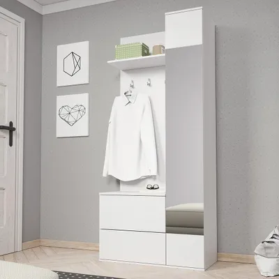 A white hallway furniture unit with a mirror, shelf, and drawers, with a white shirt hanging on a hook.