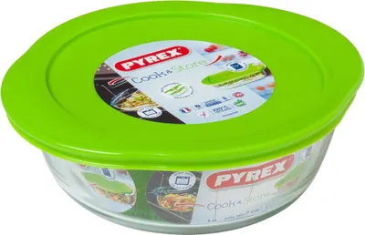 A Pyrex glass food storage container with a bright green lid, shown from a slightly elevated angle against a white background.