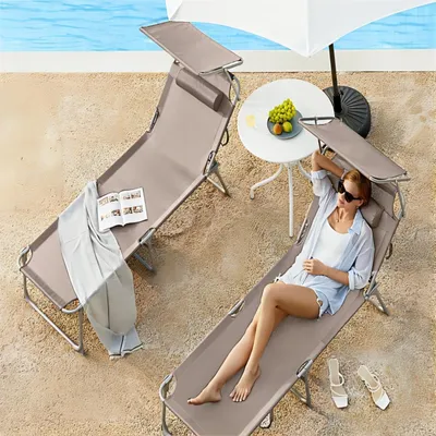 A woman relaxing on a lounge chair by a pool, with a table and fruit nearby.