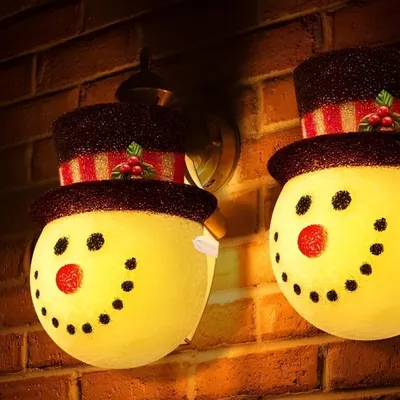 Two snowman-shaped lights mounted on a brick wall.