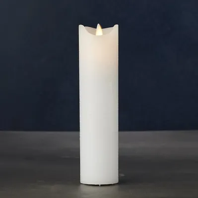 A white LED candle with a flickering flame sits on a dark surface against a dark blue background.