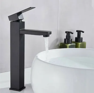 A black faucet is shown running water into a white sink. Two green soap dispensers are visible in the background.