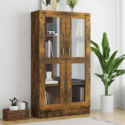 A wooden display cabinet with glass doors stands against a white wall, next to a large potted plant.