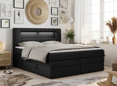 A bedroom scene featuring a black boxspring bed with an LED headboard, dressed with bedding. The room is decorated with wall art and plants, and natural light streams in from a window.