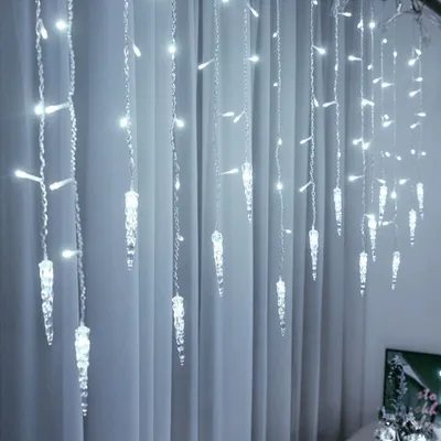 Icicle-shaped LED lights hanging in front of a white curtain.