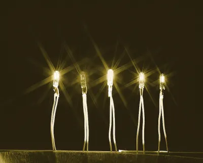 Five illuminated LEDs with starburst effects against a dark background.
