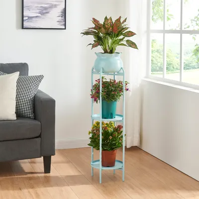 A plant stand with three tiers of plants next to a sofa and a window.