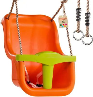 An orange baby swing with a green safety bar and harness, suspended by brown ropes with metal rings and black beads. A small tag with colorful dots is attached to one rope.