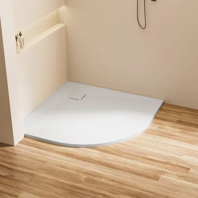 A modern bathroom corner with a white, curved shower tray on a wooden floor.
